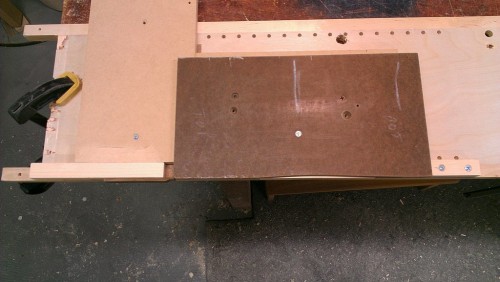 Handle secured in jig by adjustable clamping sticks on each end